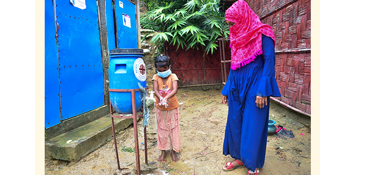 Halima and child using a hand-washing station