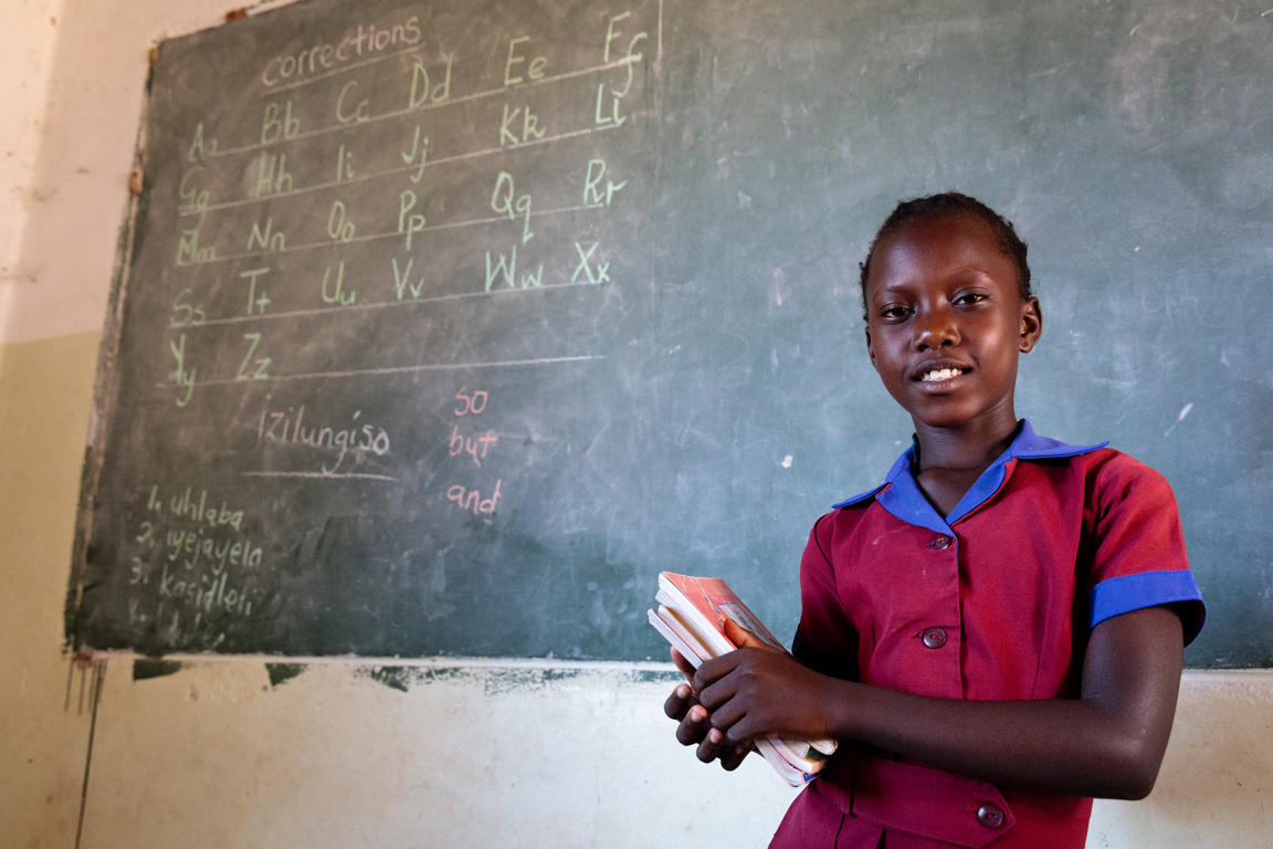 Schoolgirl in front of blackboard in Zimbabwe