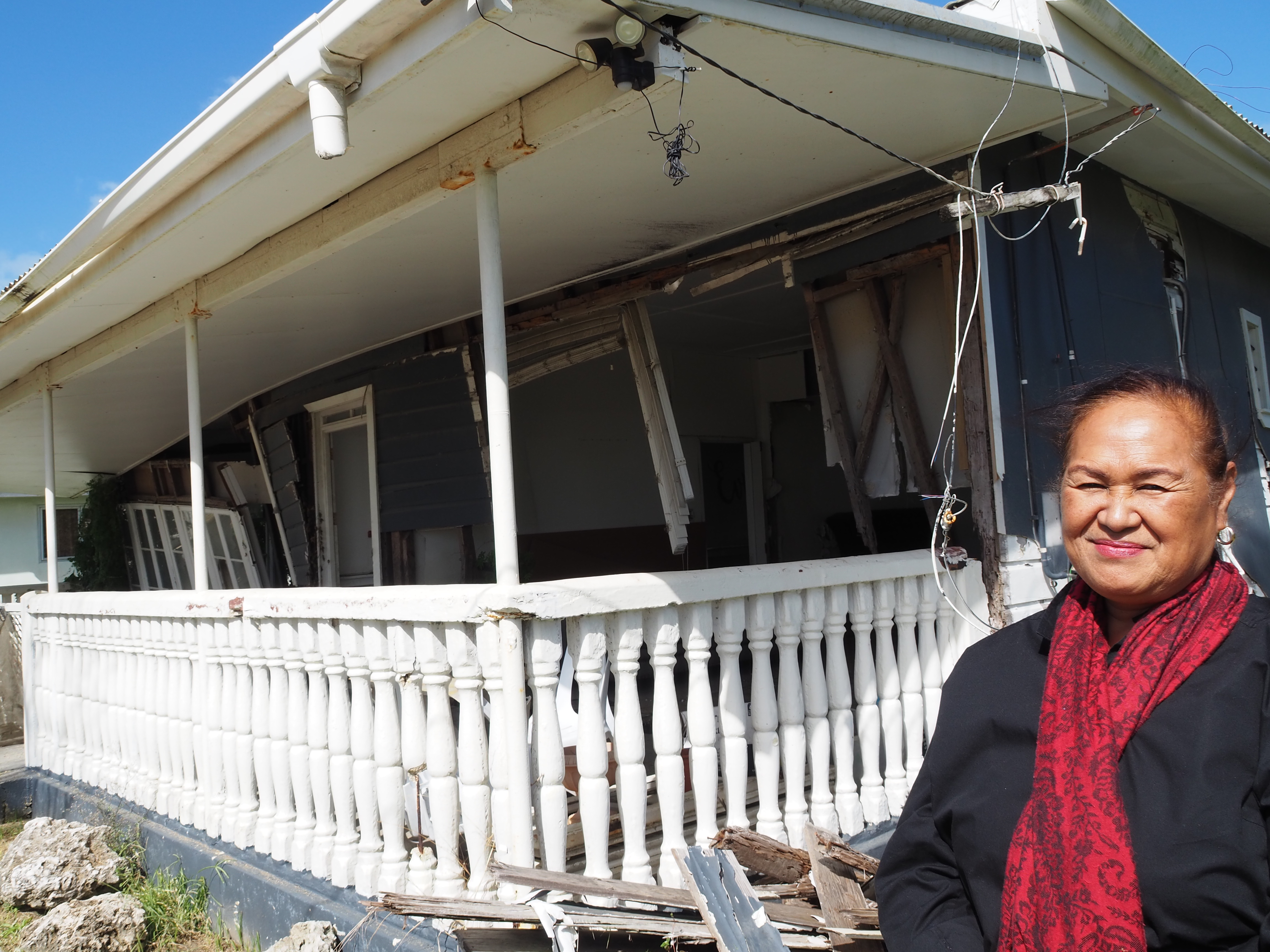Tupou standing outside a home destroyed by the tsunami in Tonga.