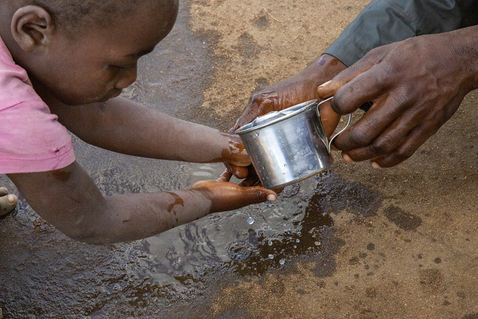 young child washing hands in river