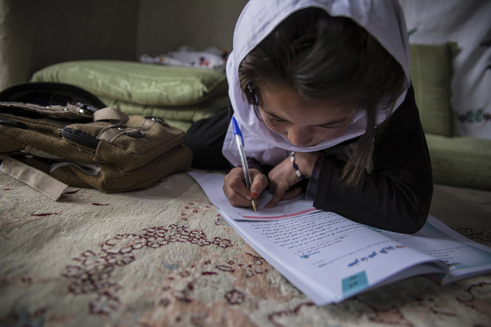 A young girl writes in a notebook in Afghanistan