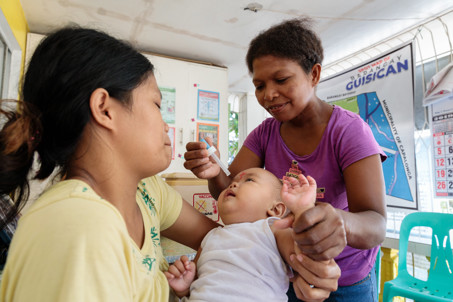 Shirley Administers Multivitamins Drops To A Child At The Local Government Health Clinic