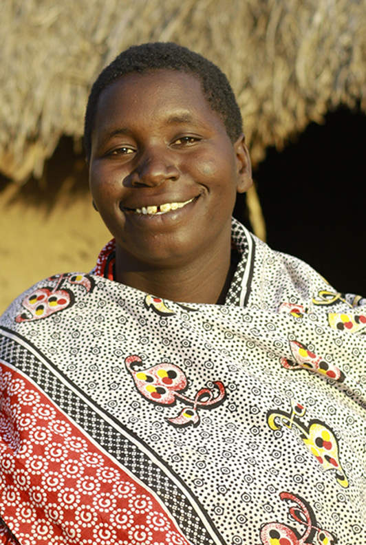 Maria standing outside of her home in Tanzania